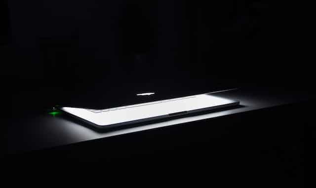 Top Trending CVES October 2022 featured image of macbook in dark room
